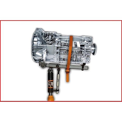 Silbernes Getriebeteil auf einer Hebebühne, mit orangefarbenem Gurt gesichert.